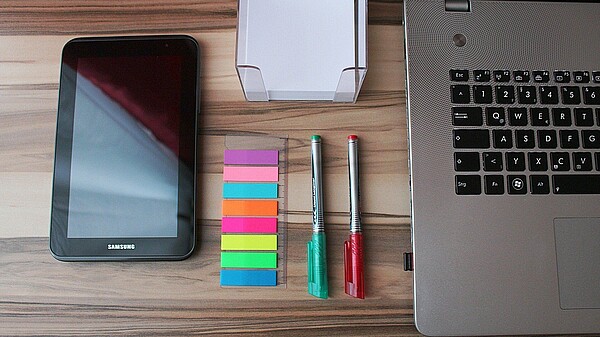 Schreibtisch mit Handy, Laptop, Stiften und Stickern