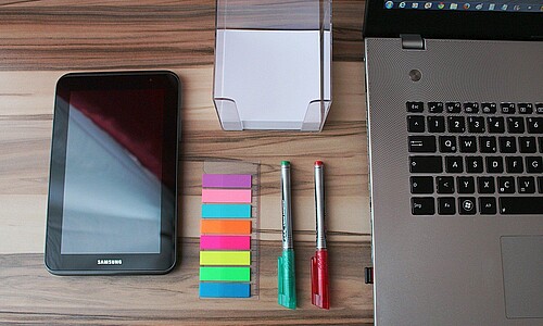 Schreibtisch mit Handy, Laptop, Stiften und Stickern
