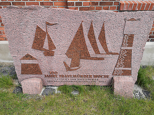 Stein mit Inschrift „100 Jahre Travemünder Woche“ und Segelbooten