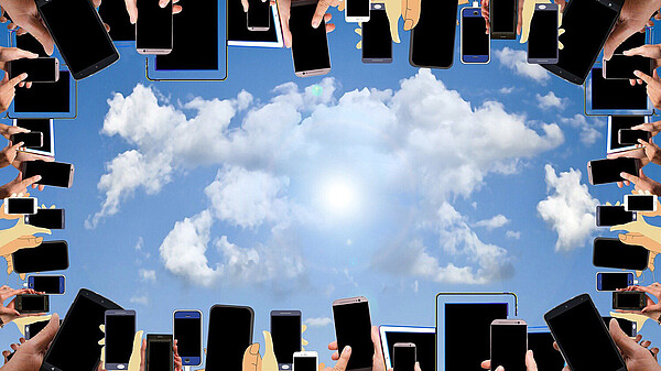 Smartphones am Bildrand, in der Mitte Himmel mit Wolken