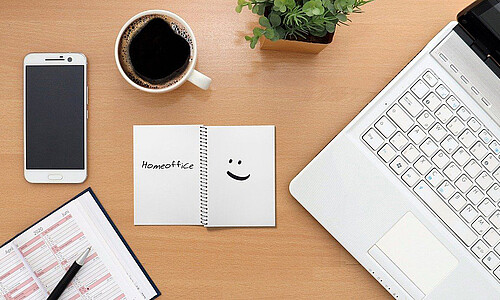 Schreibtisch mit Block, Laptop, Handy und Kaffee