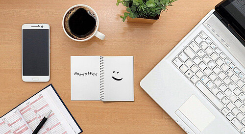 Schreibtisch mit Block, Laptop, Handy und Kaffee