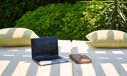 Laptop und Block auf einer Couch im Garten